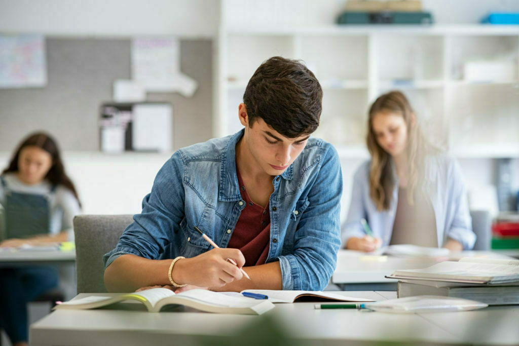 a person sitting at a desk writing on a book