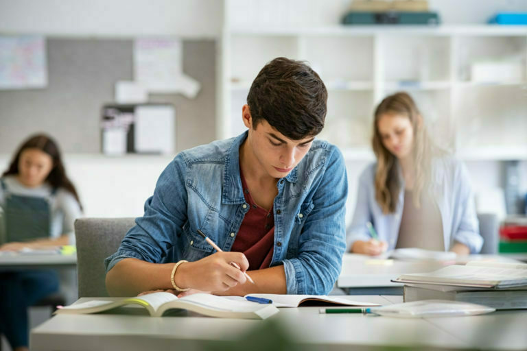 a person sitting at a desk writing on a book