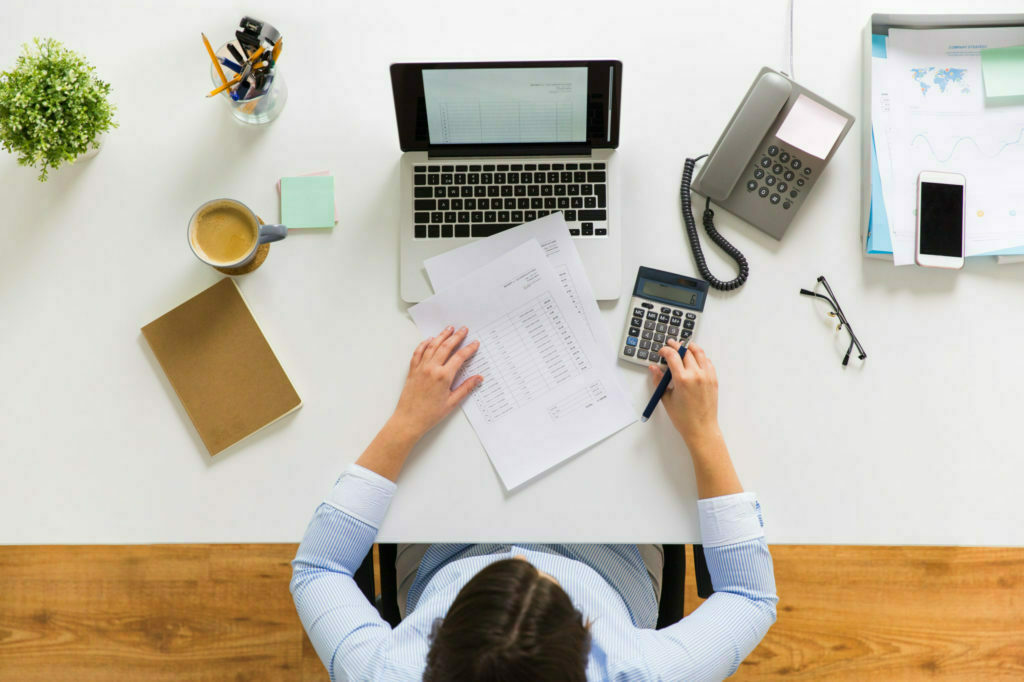 a person sitting at a desk with a laptop and papers on it