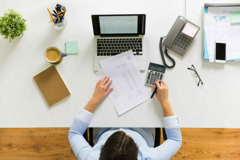 a person sitting at a desk with a laptop and papers on it