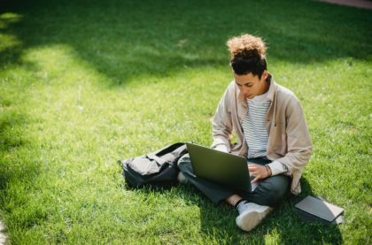 a person sitting on the grass using a laptop