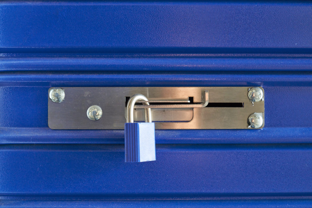 A blue locked lock on a metal barrier in a storeroom