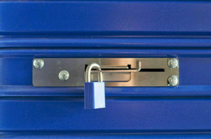 A blue locked lock on a metal barrier in a storeroom