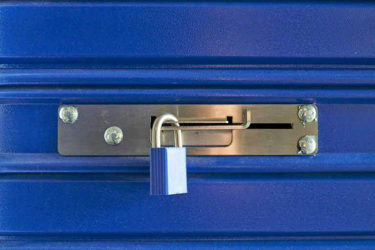 A blue locked lock on a metal barrier in a storeroom