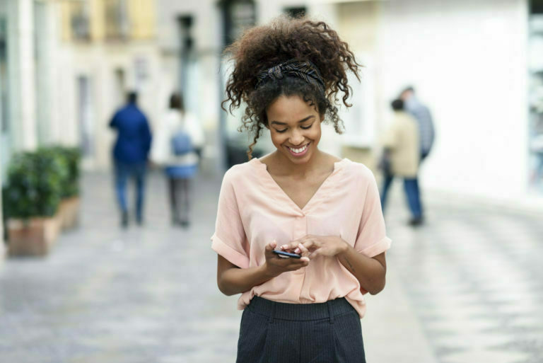 Smiling young woman using cell phone in the city